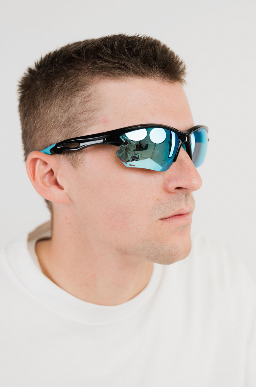 A man in a white t-shirt shown in profile wearing black sport sunglasses with mirrored blue-green lenses against a light gray background.